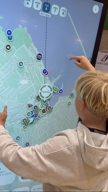 A young visitor exploring an interactive Mapzest map on a large touchscreen kiosk