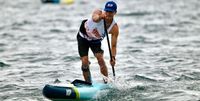 An elite stand-up paddleboard racer mid-stroke during the ICF SUP World Cup